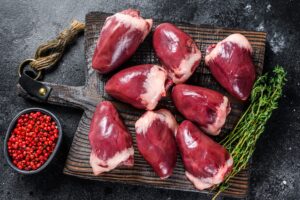Raw turkey hearts offal with herbs and spices. Black background. Top view.